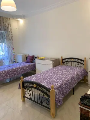 two beds in a room with purple sheets at Shmeisani Cozy Apartment in Amman