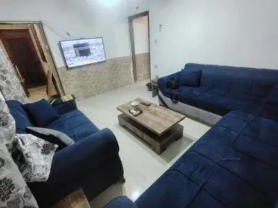a living room with blue couches and a coffee table at الشهم 10 in Irbid