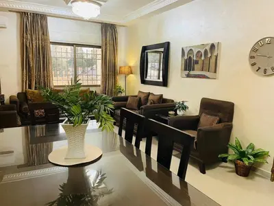 a living room with furniture and a clock on the wall at Luxurious furnished apartment for rent with hotel finishes in Amman