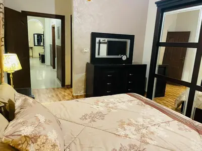 a bedroom with a bed and a television on a dresser at Luxurious furnished apartment for rent with hotel finishes in Amman