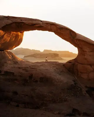 a person standing in an arch in the desert at Moon House & Sunset Tour in El Quweira