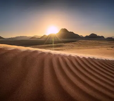 a desert with the sun setting in the background at Moon House & Sunset Tour in El Quweira