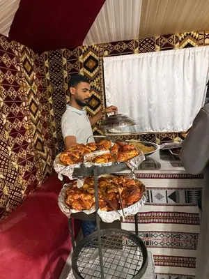 a man standing behind a counter with trays of food at Nala Luxury Camp & Bubbles Hotel in Wadi Rum