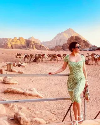 a woman in a green dress standing next to a fence in a desert at Nala Luxury Camp & Bubbles Hotel in Wadi Rum