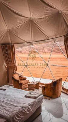 a bedroom with a bed and a large window at Nala Luxury Camp & Bubbles Hotel in Wadi Rum