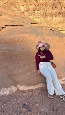 a woman sitting on the side of a rock at wadi rum planet camp in Disah