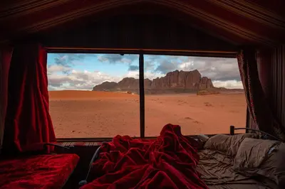 a bed in a room with a view of the desert at Stars Night Camp in Wadi Rum