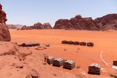 a group of buildings in the desert with mountains at Dune Camp Tours in Wadi Rum