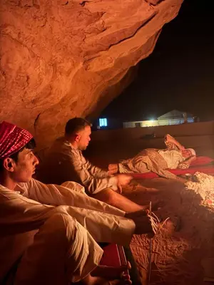 a group of men sitting on beds in a cave at Dune Camp Tours in Wadi Rum