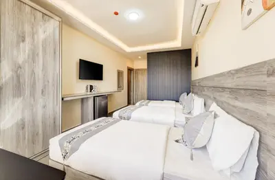 a hotel room with three beds and a tv at aqaba hills hotel in Aqaba