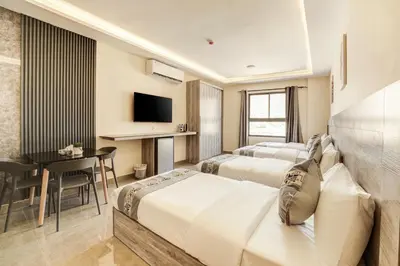 a hotel room with three beds and a table at aqaba hills hotel in Aqaba