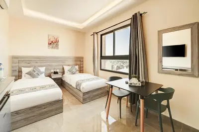 a hotel room with two beds and a desk at aqaba hills hotel in Aqaba