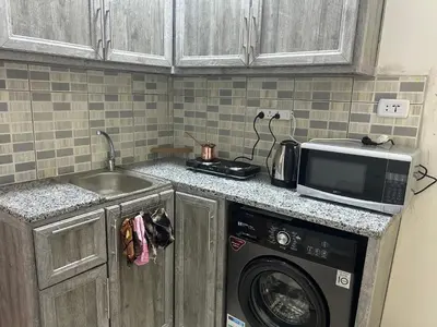 a kitchen with a washing machine and a microwave at One bedroom apartment in the heart of west Amman in Amman