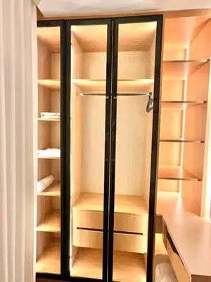 an empty closet with wooden shelves and glass doors at Brand New Stylish Luxe Apartment Near US Embassy Abdoun in Amman