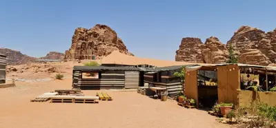 a building in the desert with mountains in the background at Martian Desert Camp in Wadi Rum