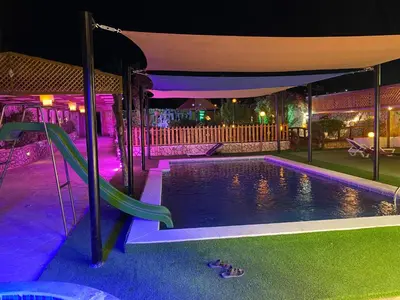 a swimming pool at night with a slide at مزرعه الخال in Al Kafrayn