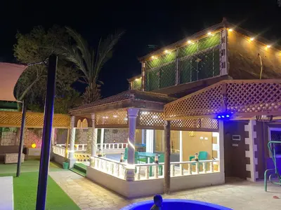 a house with a deck at night with lights at مزرعه الخال in Al Kafrayn