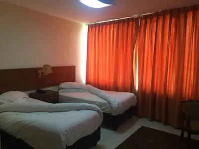 a hotel room with two beds and an orange curtain at Zaina Plaza Hotel in Amman