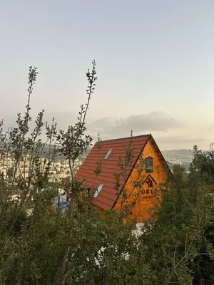 an orange barn with a red roof on a hill at أكواخ المها oryx cottage in Ajloun