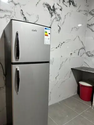 a stainless steel refrigerator in a kitchen with marble walls at شاليه كل الفصول in Dawqarah
