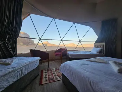 a room with two beds and a large window at وادي رم مخيم in Wadi Rum
