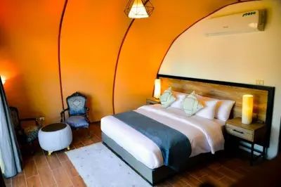 a bedroom with a large bed with an orange wall at Luxury Spiral Camp in Maḩaţţat Dīsah
