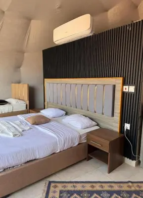 a bedroom with a large bed with a wooden headboard at RUM iSLAND bubble LUXURU CAMP in Wadi Rum