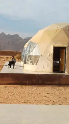 a couple sitting in front of a tent in the desert at RUM iSLAND bubble LUXURU CAMP in Wadi Rum
