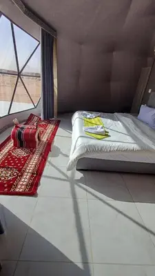 a bedroom with a bed and a rug and a window at RUM iSLAND bubble LUXURU CAMP in Wadi Rum