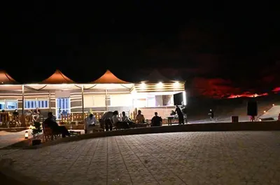 a group of people sitting outside of a building at night at ATAYA sunrise camp in Disah