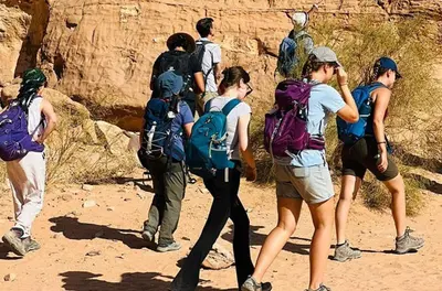 a group of people with backpacks walking on a trail at ATAYA sunrise camp in Disah