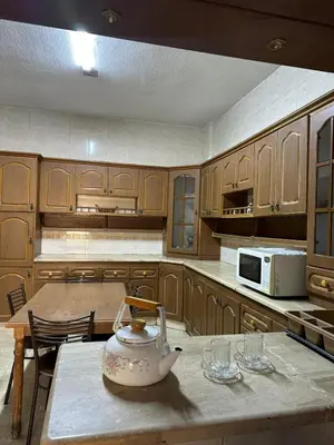 a kitchen with wooden cabinets and a tea kettle on a table at 3 Bedroom Family Apartment in Amman in Amman