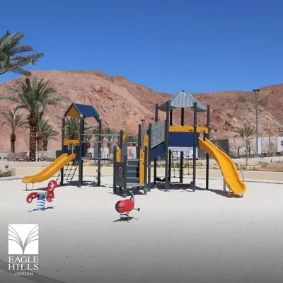 a playground with yellow and blue equipment in the desert at شقه بغرفة نوم في قريه الراحة one bedroom apartment in alraha village in Al Jafr