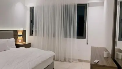 a white bedroom with a bed and a desk and window at شقه بغرفة نوم في قريه الراحة one bedroom apartment in alraha village in Al Jafr