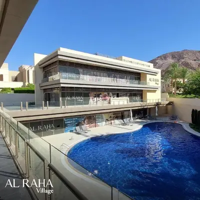 a building with a large swimming pool in front of it at شقه بغرفة نوم في قريه الراحة one bedroom apartment in alraha village in Al Jafr