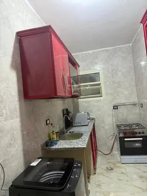 a small kitchen with a sink and red cabinets at Marco inn in Amman