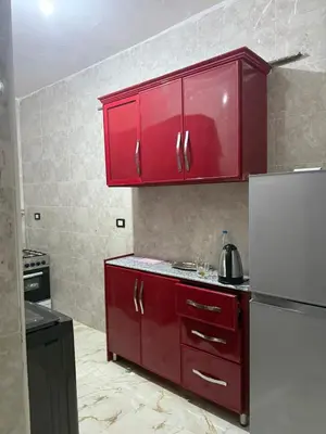a kitchen with red cabinets and a white refrigerator at Marco inn in Amman