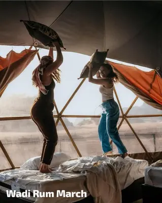 two women standing on a bed holding umbrellas at Wadi Rum March in Wadi Rum