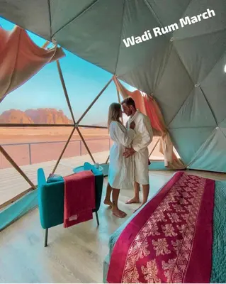 a man and woman kissing under an umbrella at Wadi Rum March in Wadi Rum