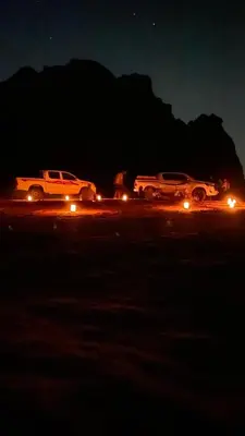 three trucks parked in a parking lot at night at Desert Horizon Camp in Disah