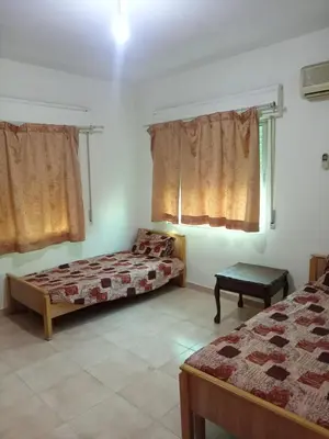 a bedroom with two beds and a window with curtains at Al Martini Building Number 11 in Amman
