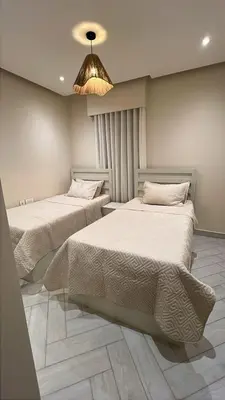 a bedroom with two beds and a chandelier at واحة ايلة ازور in Aqaba