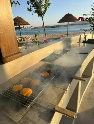 a grill with bread on top of a counter next to the beach at واحة ايلة ازور in Aqaba