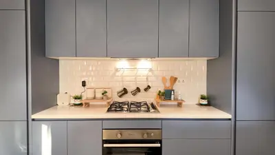 a kitchen with gray cabinets and a stove top oven at واحة ايلة ازور in Aqaba