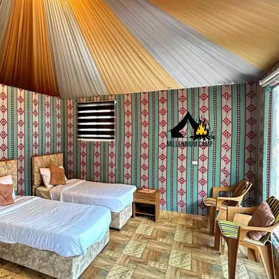 a room with two beds and a table and chairs at millennium camp in Wadi Rum