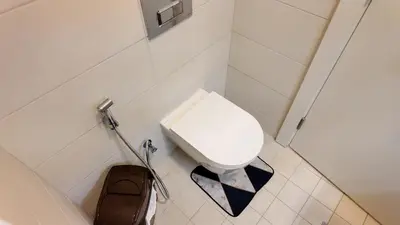 a small white toilet in a bathroom with a bag at واحة ايلة ازور in Aqaba