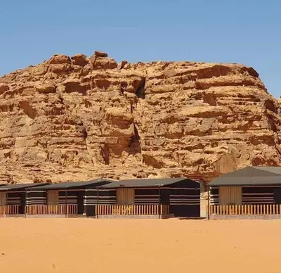 a building in the desert next to a mountain at Wadi Rum Aura Camp in Wadi Rum