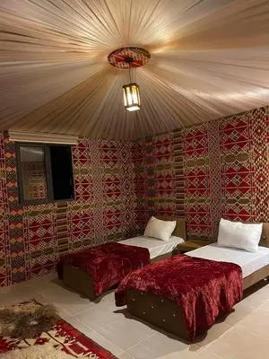 two beds in a room with red wallpaper at Wadi Rum Aura Camp in Wadi Rum