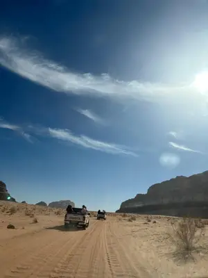 two trucks driving down a dirt road in the desert at Bedouin Luxe Camp & Tour in Wadi Rum