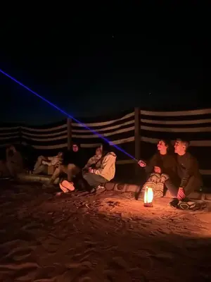 a group of people sitting around a fire at night at Bedouin Luxe Camp & Tour in Wadi Rum